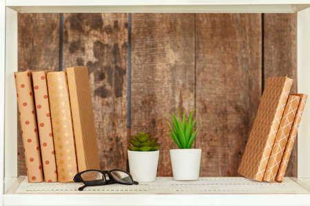 Stylish white bookshelf against grunge wooden wallの写真素材