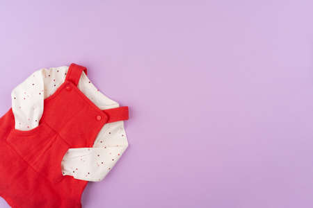 Baby girl clothes on lilac pastel backgroundの写真素材