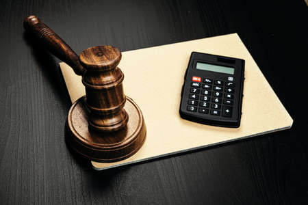 Wooden judges gavel and calculator on table