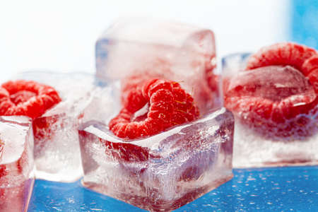 Ice cubes with frozen berries inside close up