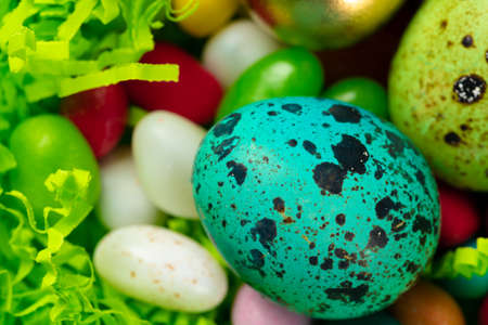 Egg shell with colorful candies inside in a decorative Easter nest