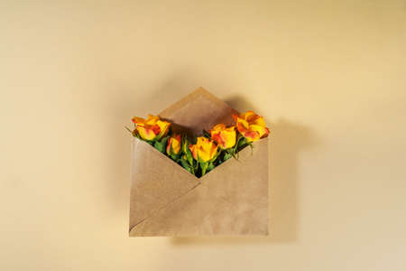 Craft paper envelope with yellow roses on beige backgroundの写真素材
