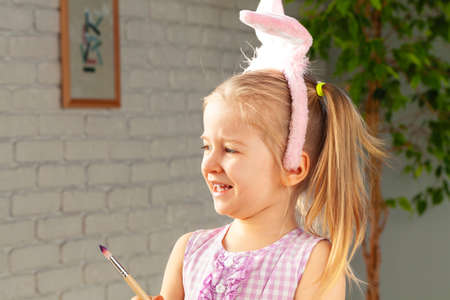 Portrait of a cute girl with paintbrush ready to paint eggs