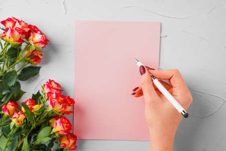 Top view of a pink paper letter and flowers with copy space