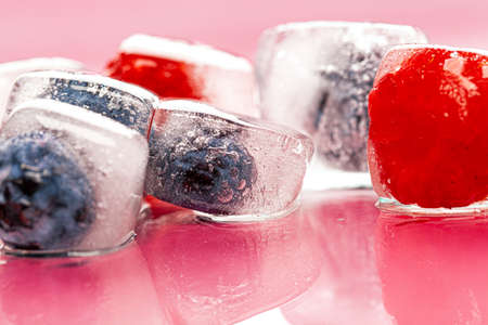 Fresh berries frozen in ice cubes for drinksの写真素材