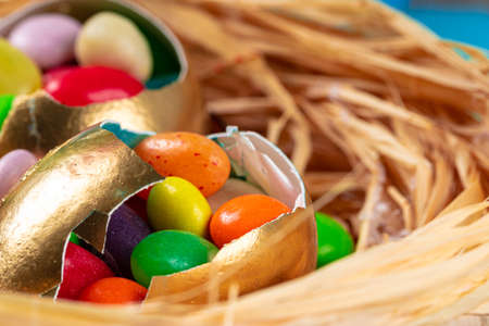 Egg shell with colorful candies inside in a decorative Easter nestの写真素材