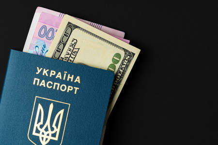 Ukrainian citizen passport with US dollars and Ukrainian hryvnia banknotes inside. Going abroad, exchange rate conceptの写真素材