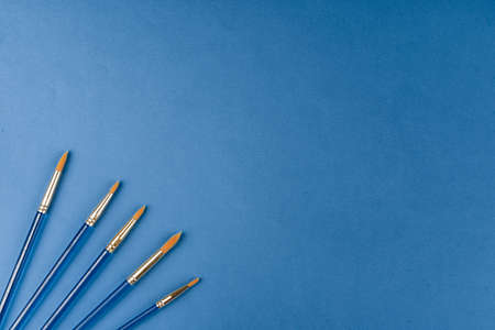 Blue paint brushes on classic blue background, view from aboveの写真素材