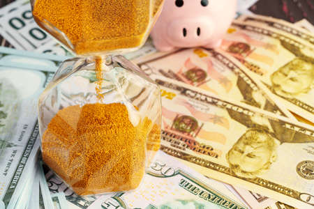 Time and money business concept. Sandglass and money