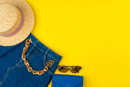 Trendy woman outfit with accessories on bright yellow background