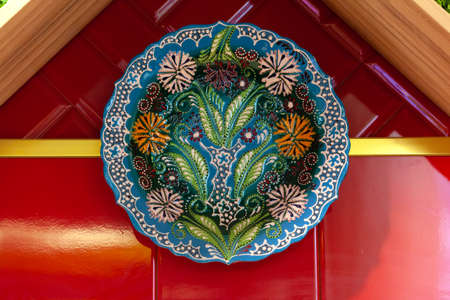 Colorful ceramic painted plates hanging on the red wall