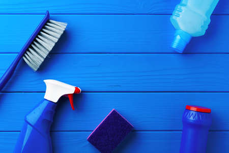 Household cleaning supplies on blue wooden background flat lay