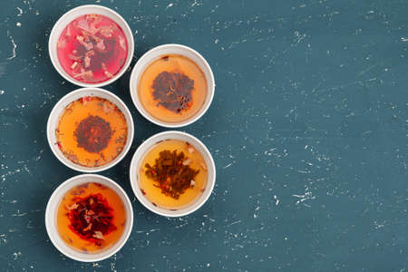 Tea concept. Different kinds of dry tea in ceramic bowls and cups of aromatic teaの写真素材