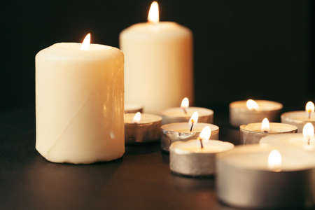 Many candles burning at night. Many candle flames glowing on dark backgroundの写真素材