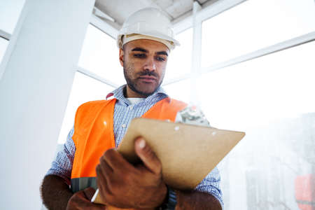 Foreman at work on construction site checking his notes on clipboardの写真素材