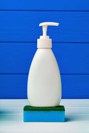 Liquid soap bottle and cleaning sponge against blue wooden background, close upの写真素材