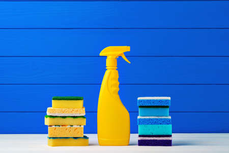 Stack of new cleaning sponges and liquid detergent against blue wooden background, close upの写真素材