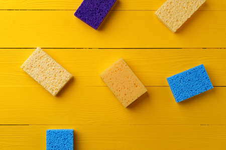 Cleaning sponges on yellow wooden background flat layの写真素材