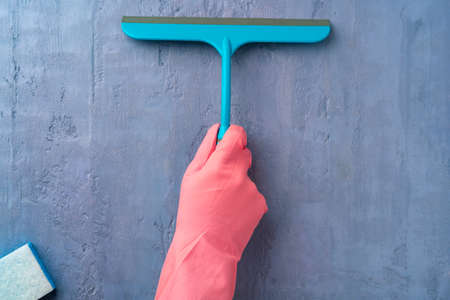 Hand in pink glove holding window cleaning brushの写真素材