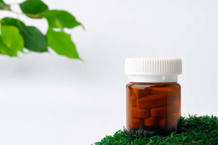 Brown glass bottle with pills on moss, dietary supplementの写真素材