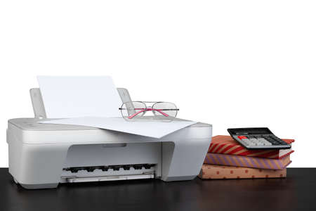 Printer and stack of books on black table against white backgroundの写真素材