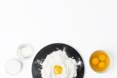 Raw egg yolk in pile of flour on white backgroundの写真素材