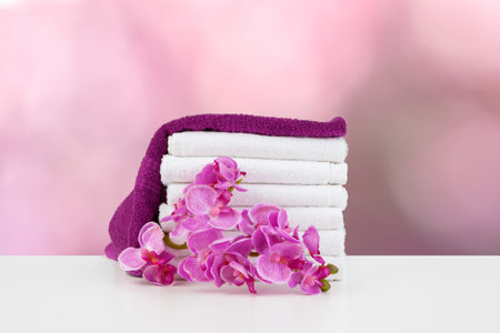 Towels with flowers on light table against blurred backgroundの写真素材