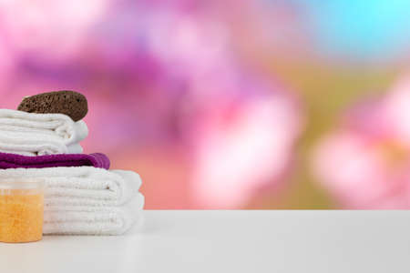 Spa still life with towels and skincare cosmetics against blurred background