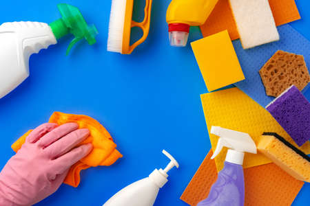 Ð¡leaning supplies with hands in rubber gloves on blue background