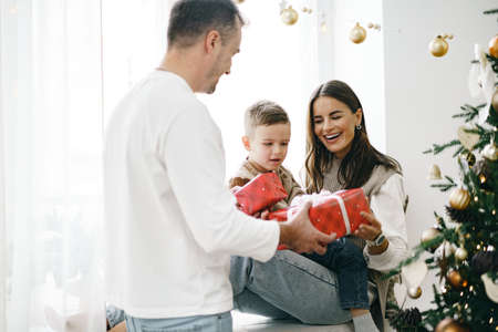Smiling parents giving Christmas present to son at home