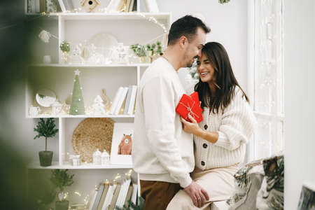 Young cheerful couple in love with present for Christmasの写真素材