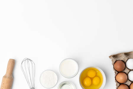 Metal whisk and eggs for cooking isolated on whiteの写真素材