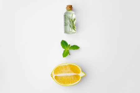 Essential oil bottles and citrus fruit on white background