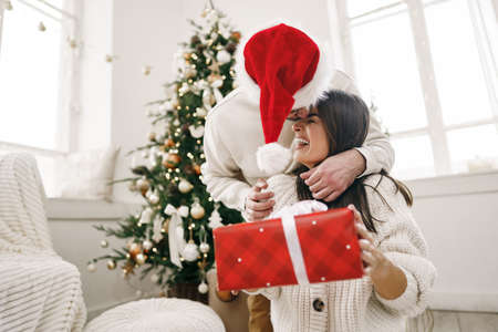 Young cheerful couple in love with present for Christmasの写真素材