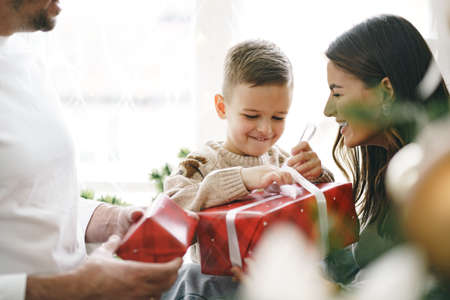 Smiling parents giving Christmas present to son at homeの写真素材