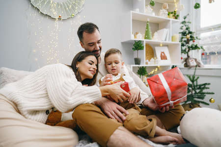 Smiling parents giving Christmas present to son at homeの写真素材