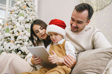 Happy family having fun on digital tablet in bed on Christmas
