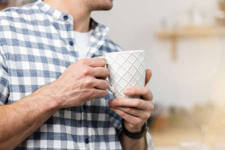 Unrecognizable man in checkered shirt holding white cup in handsの写真素材