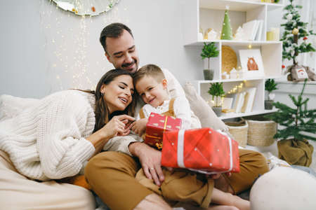 Smiling parents giving Christmas present to son at home