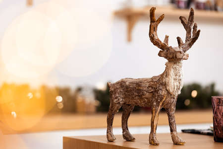 Wooden reindeer on wooden table with christmas garland lightsの写真素材