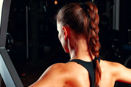 Young attractive woman doing exercises for arms in a training machine
