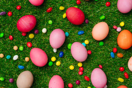 Colored eggs and vibrant candies on grass. Easter compositionの写真素材