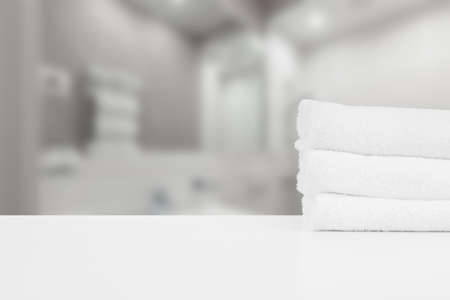 Stacked white spa towels on table against blurred backgroundの写真素材