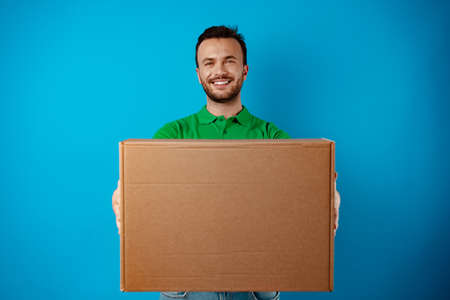 Delivery man with box in studio against blue backgroundの写真素材
