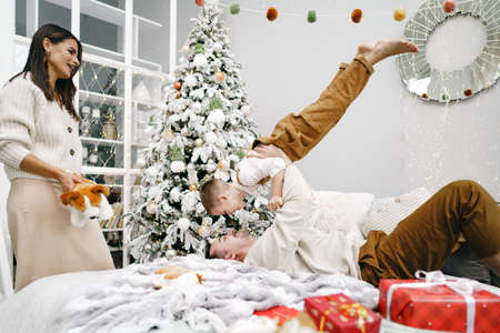 Mother, father and son having fun on bed on Christmas dayの写真素材