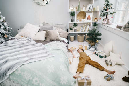Little boy with Christmas gifts lying down on the floorの写真素材