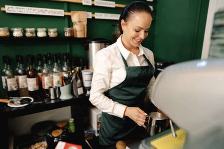 Caucasian female barista at work making coffeeの写真素材