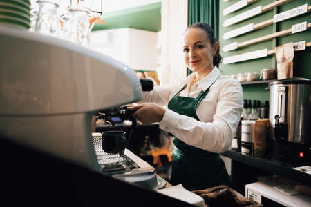 Caucasian female barista at work making coffeeの写真素材