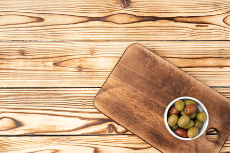 Olives in a bowl on wooden background, top viewの写真素材