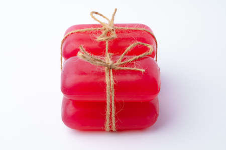Red handmade soap bars tied with ribbon on white background